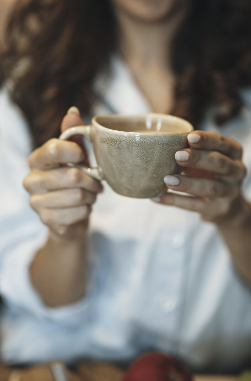 Hands cradling a warm cup at a kitchen counter